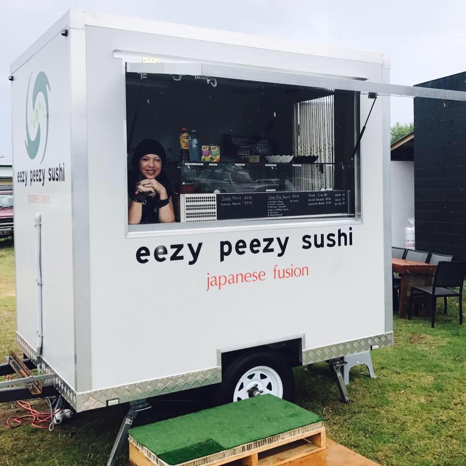 The owner smiling at the Eezy Peezy Sushi food truck window, with the Japanese Fusion brand name visible