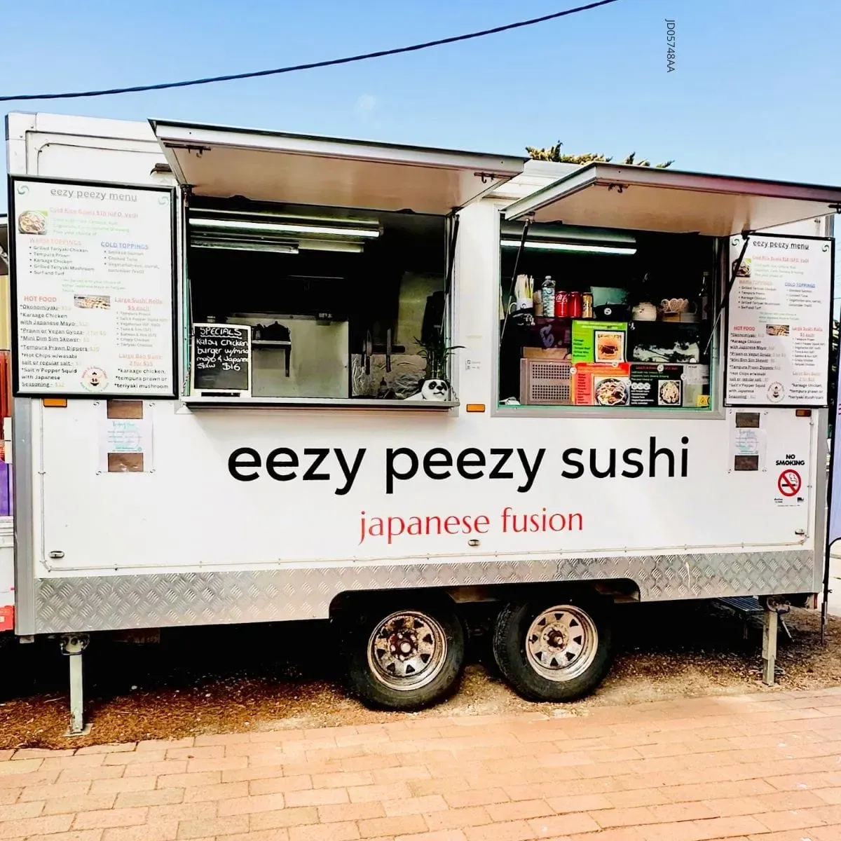 The Eezy Peezy Sushi food truck parked and open for service, with the full brand name and Japanese Fusion tagline visible on the white truck exterior.